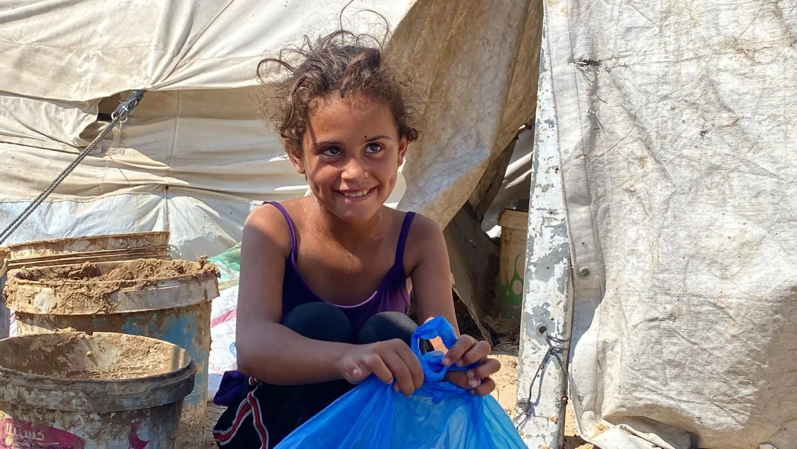 A girl in Gaza smiles holding a Euro Relief aid parcel